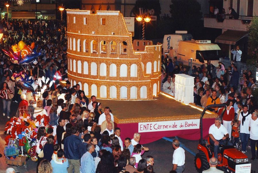 Il Dolcione a forma di Colosseo, fatto di pasta e zucchero, illuminato di notte in mezzo alla folla